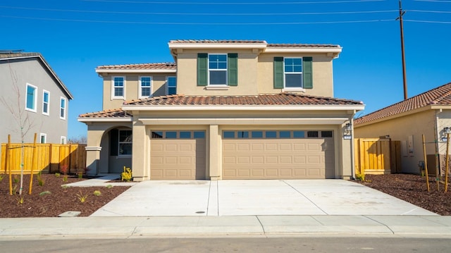 mediterranean / spanish house featuring an attached garage, fence, driveway, and stucco siding