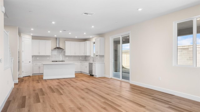 kitchen featuring tasteful backsplash, visible vents, wall chimney range hood, white cabinetry, and stainless steel dishwasher