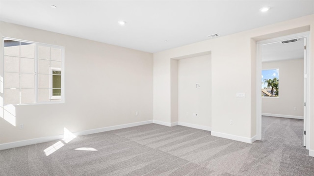 carpeted empty room with baseboards, visible vents, and recessed lighting