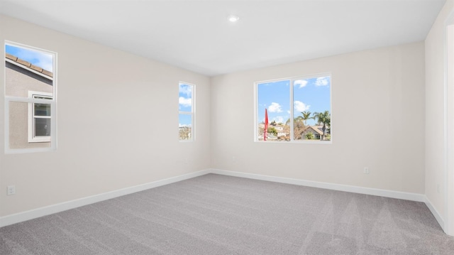 empty room featuring a wealth of natural light, baseboards, and carpet floors