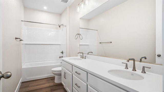 bathroom featuring double vanity, a sink, toilet, and wood finished floors