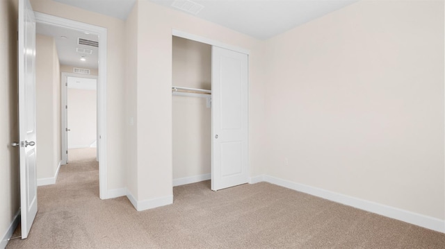 unfurnished bedroom with light carpet, visible vents, a closet, and baseboards