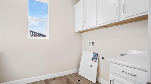 laundry area with light wood-type flooring, baseboards, cabinet space, and washer hookup