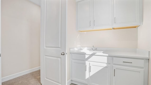 laundry room featuring a sink, baseboards, and light carpet