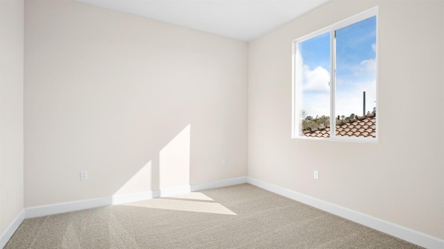 carpeted empty room featuring baseboards