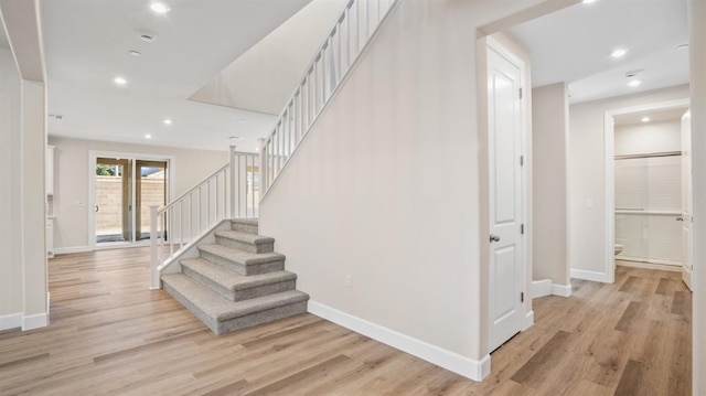 stairway with wood finished floors, baseboards, and recessed lighting