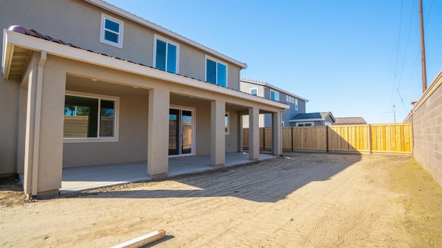 rear view of house with a patio area, fence, and stucco siding