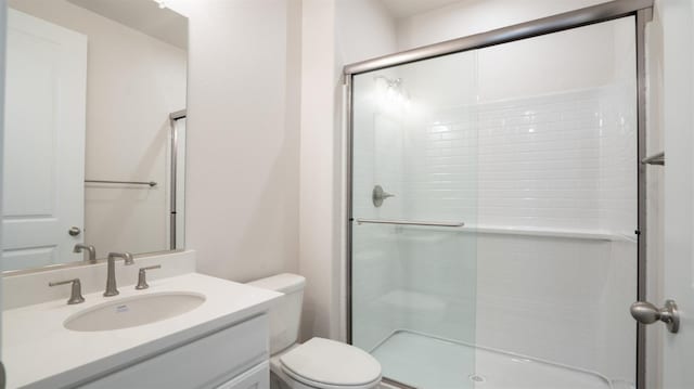 bathroom featuring vanity, toilet, and a stall shower