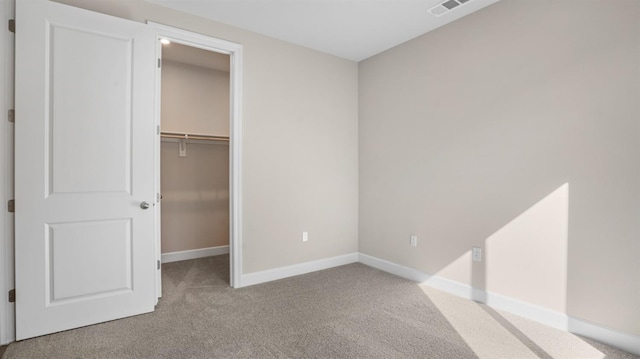 unfurnished bedroom featuring visible vents, a walk in closet, baseboards, carpet flooring, and a closet