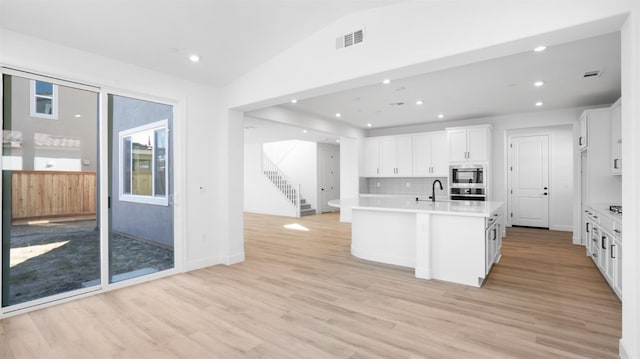 kitchen with light countertops, light wood-style floors, appliances with stainless steel finishes, white cabinetry, and backsplash