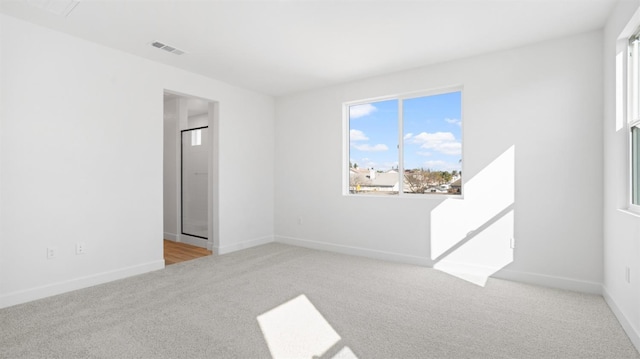 empty room with light carpet, baseboards, and a wealth of natural light