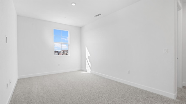 carpeted spare room featuring visible vents and baseboards