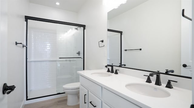 full bathroom featuring a shower stall, toilet, wood finished floors, and a sink