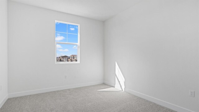 spare room featuring carpet flooring and baseboards