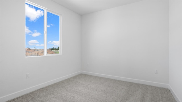 carpeted empty room featuring baseboards