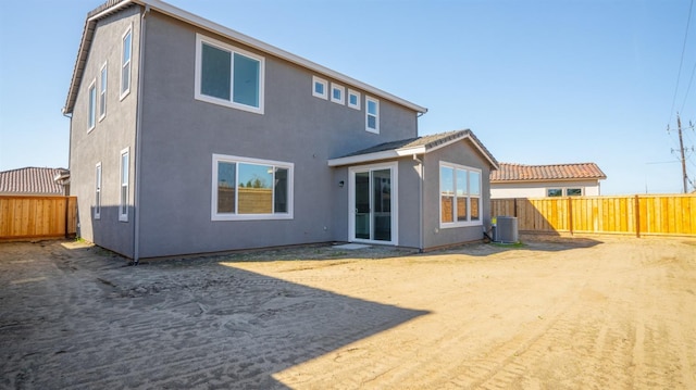 rear view of property with stucco siding, central AC unit, and a fenced backyard