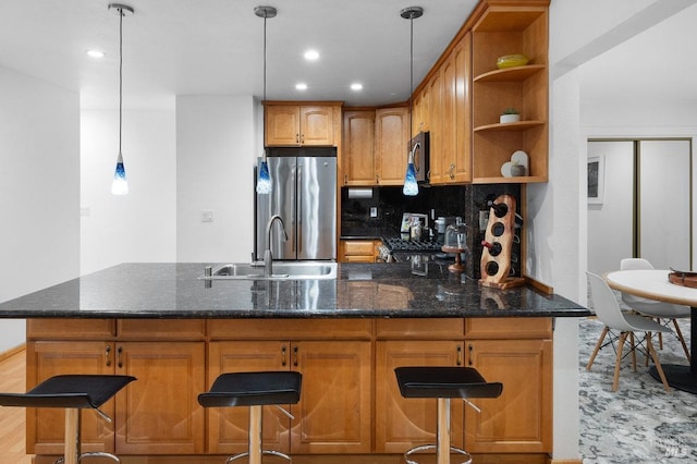 kitchen featuring hanging light fixtures, sink, light wood-type flooring, appliances with stainless steel finishes, and tasteful backsplash