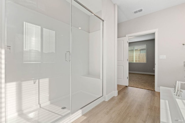 bathroom with a shower with shower door and wood-type flooring