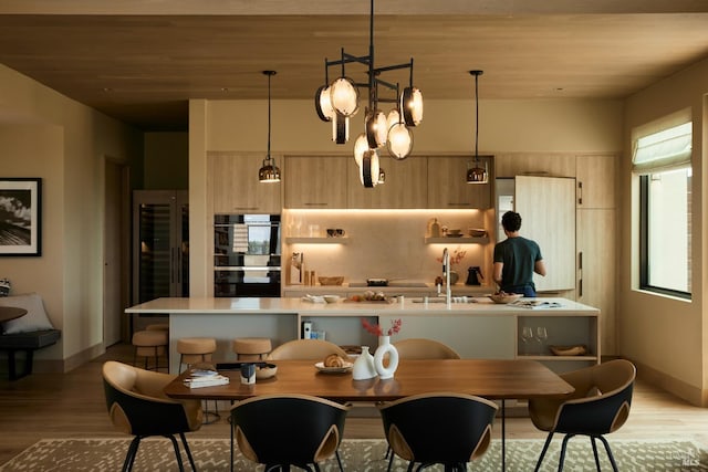 kitchen with light brown cabinetry, light countertops, modern cabinets, dobule oven black, and light wood-type flooring