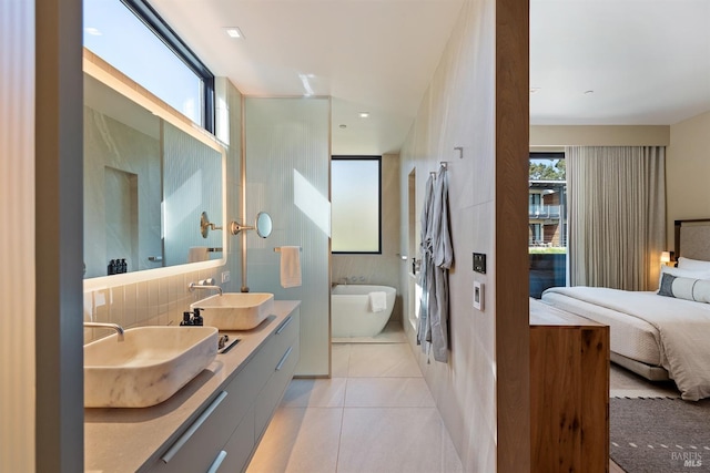 ensuite bathroom featuring connected bathroom, a freestanding tub, tile patterned flooring, and a sink