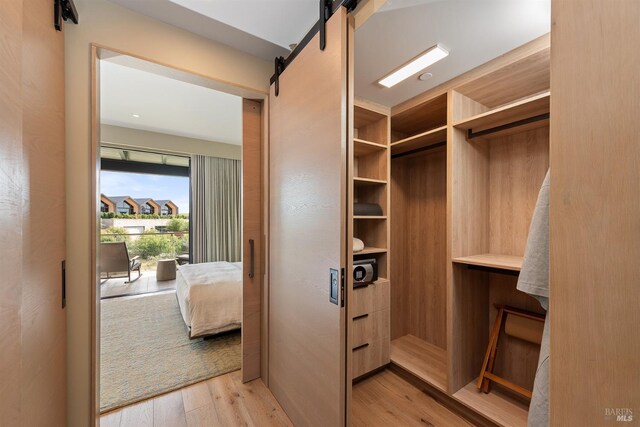 spacious closet featuring a barn door and light wood finished floors