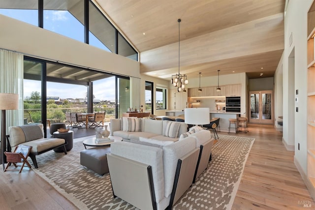 living room with light hardwood / wood-style flooring, high vaulted ceiling, a notable chandelier, and a wealth of natural light