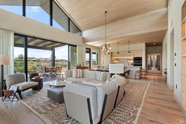 living area with a notable chandelier, high vaulted ceiling, and light wood-style floors