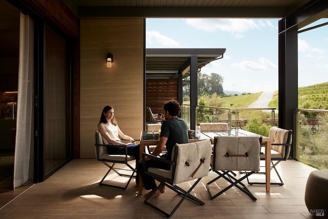 sunroom with expansive windows, wood finished floors, a healthy amount of sunlight, and wood walls