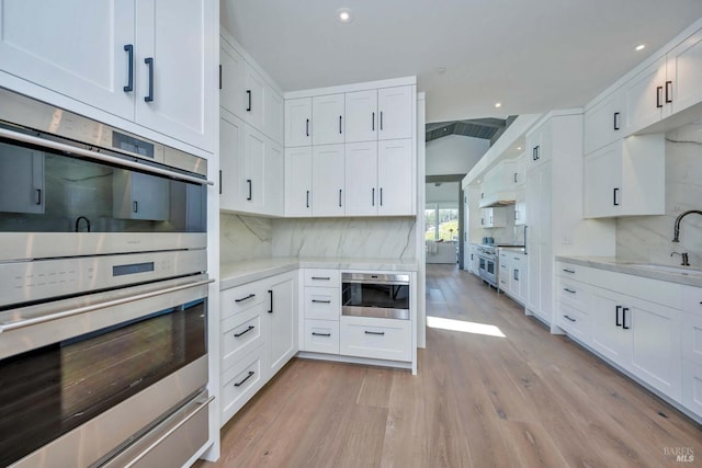 kitchen featuring appliances with stainless steel finishes, sink, white cabinets, and light hardwood / wood-style floors