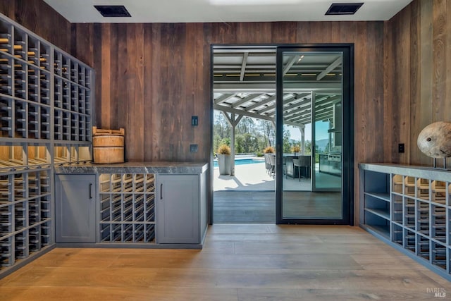 wine room featuring light hardwood / wood-style floors and wooden walls