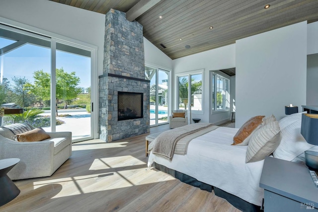 bedroom featuring a stone fireplace, access to exterior, wood finished floors, beam ceiling, and high vaulted ceiling