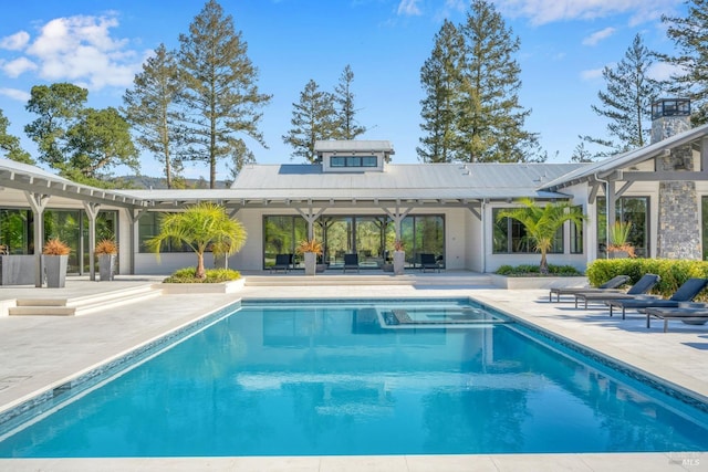 rear view of house featuring a patio, metal roof, and an outdoor pool