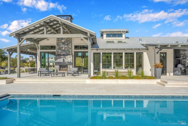 exterior space featuring a patio, a gazebo, an outdoor stone fireplace, and an outdoor pool