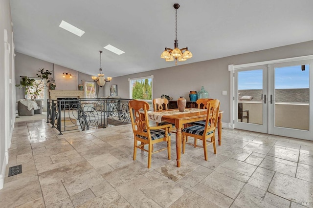 dining space with french doors, vaulted ceiling with skylight, and a chandelier