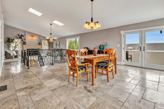 dining space featuring vaulted ceiling with skylight and an inviting chandelier