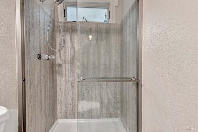 bathroom featuring toilet and a shower with shower door