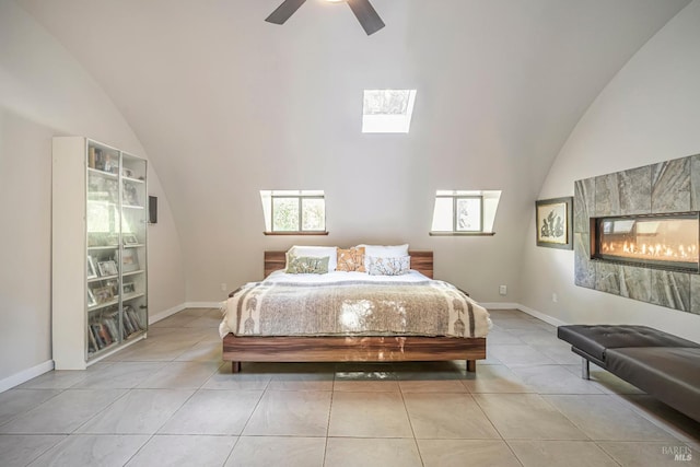 tiled bedroom featuring ceiling fan, high vaulted ceiling, a skylight, and multiple windows