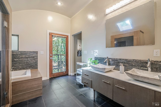 bathroom with tile patterned flooring, a washtub, vanity, high vaulted ceiling, and a skylight