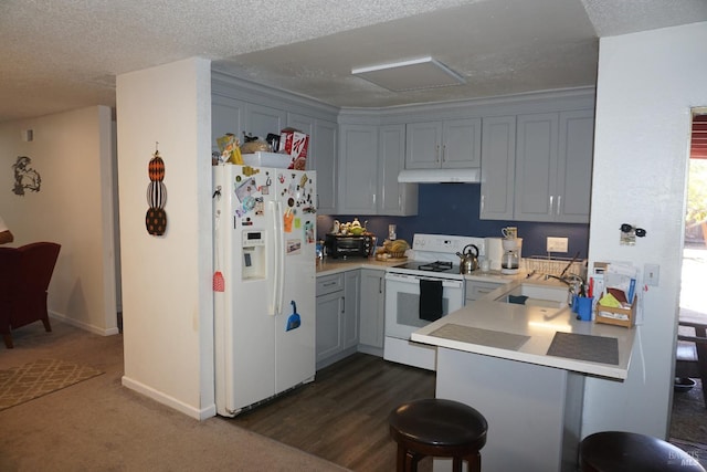 kitchen featuring white appliances, sink, a textured ceiling, kitchen peninsula, and dark wood-type flooring