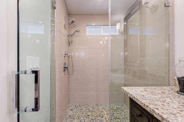 bathroom featuring a shower with door and vanity