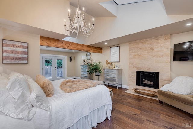 bedroom with french doors, a high ceiling, a notable chandelier, a fireplace, and dark hardwood / wood-style flooring