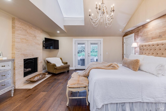 bedroom with a large fireplace, dark hardwood / wood-style flooring, access to exterior, a chandelier, and french doors