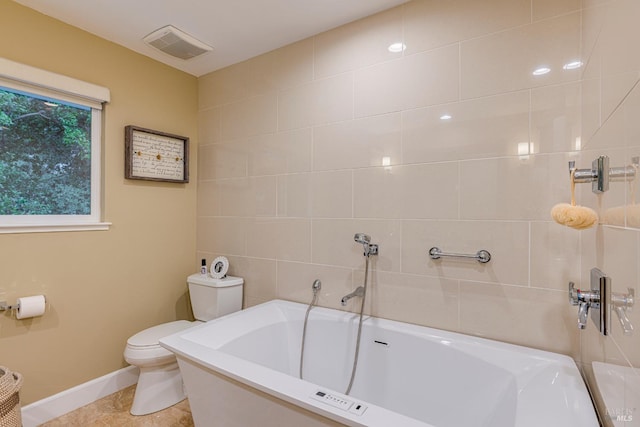 bathroom with toilet, a tub to relax in, and tile patterned floors