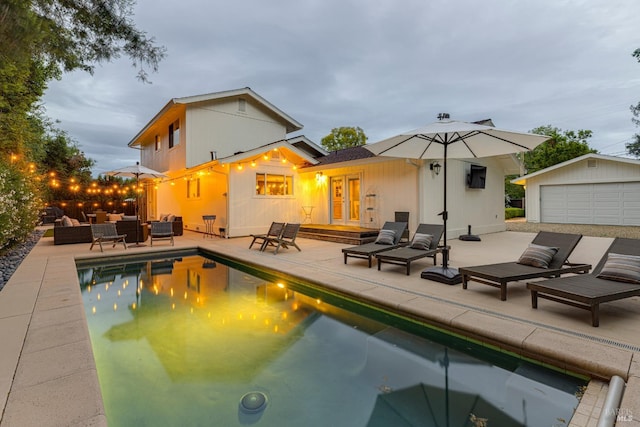 view of pool featuring a patio area, an outdoor structure, french doors, outdoor lounge area, and a garage