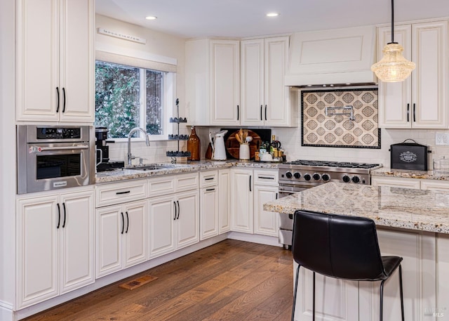 kitchen with dark wood-type flooring, sink, decorative light fixtures, white cabinetry, and appliances with stainless steel finishes