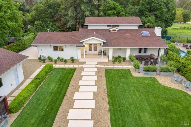 rear view of property with french doors, a patio area, and a lawn