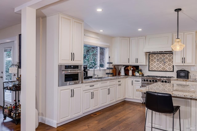 kitchen featuring appliances with stainless steel finishes, sink, backsplash, decorative light fixtures, and dark wood-type flooring