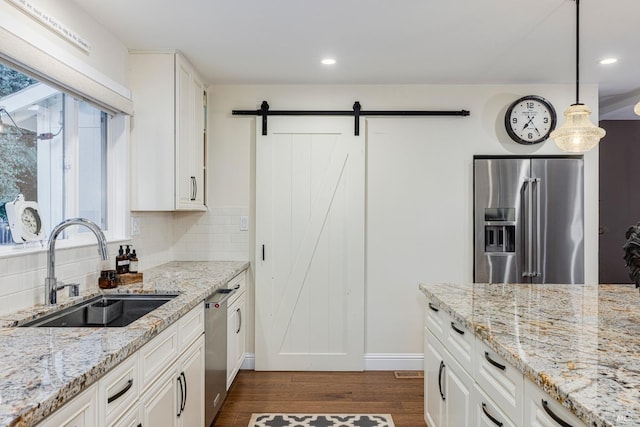 kitchen featuring white cabinetry, appliances with stainless steel finishes, decorative light fixtures, and a wealth of natural light