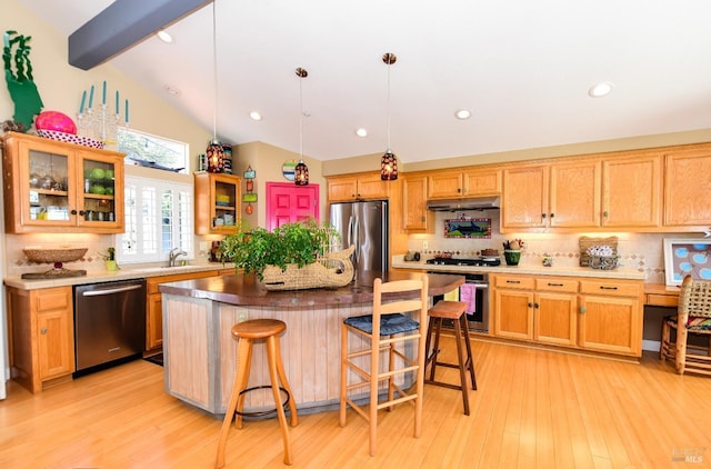 kitchen featuring a breakfast bar, under cabinet range hood, lofted ceiling with beams, backsplash, and stainless steel appliances