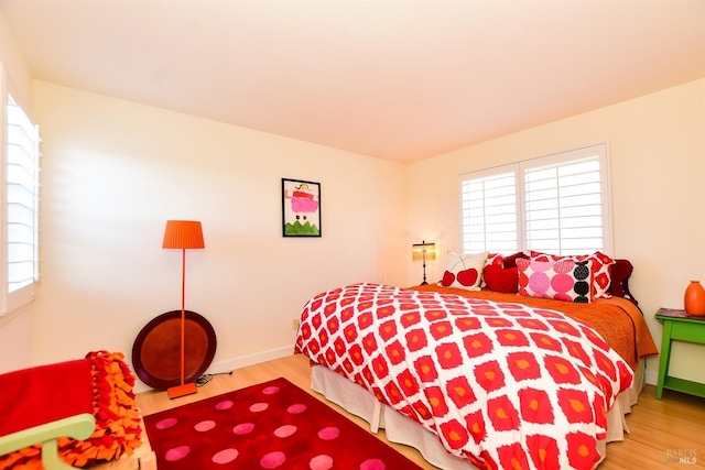 bedroom with multiple windows and hardwood / wood-style flooring